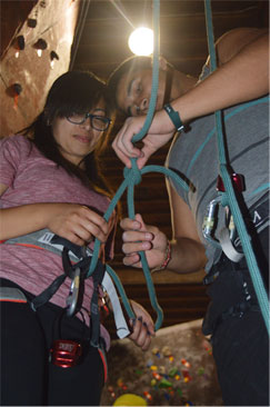 A LEAP volunteer shows a student “the ropes” of climbing on the rock wall.