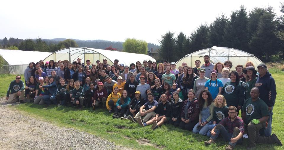 Large goup of volunteers stand in front of hoop houses at Potawot at YES Serve-a-Thon