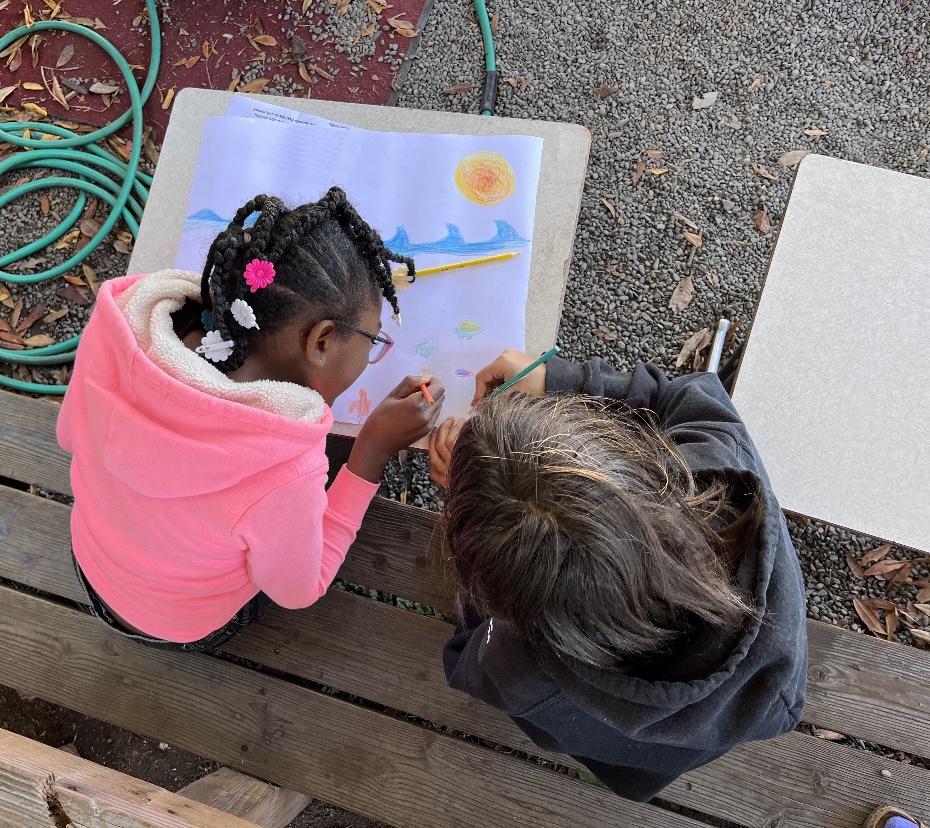 Two students at Trillium draw together outside