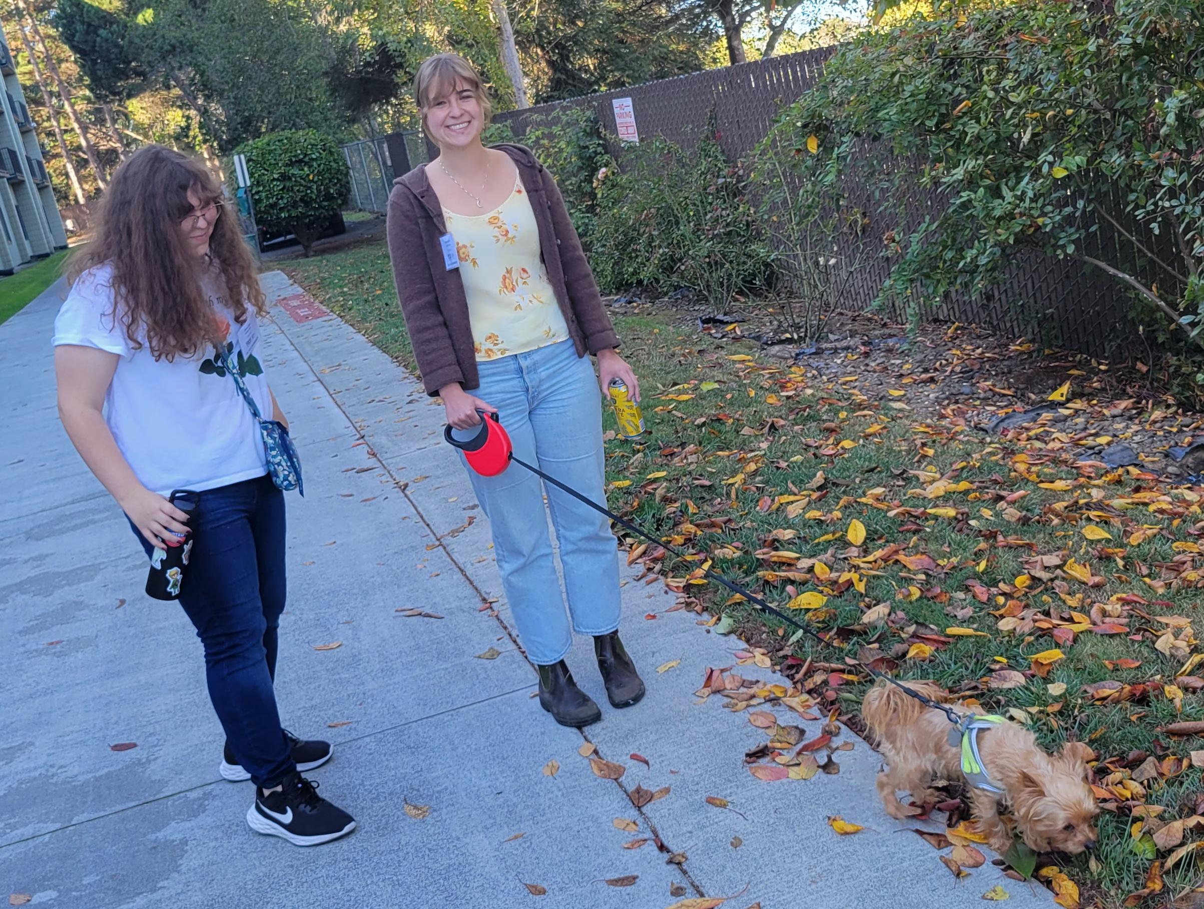 two volunteers walk a small tan dog at Silvercrest