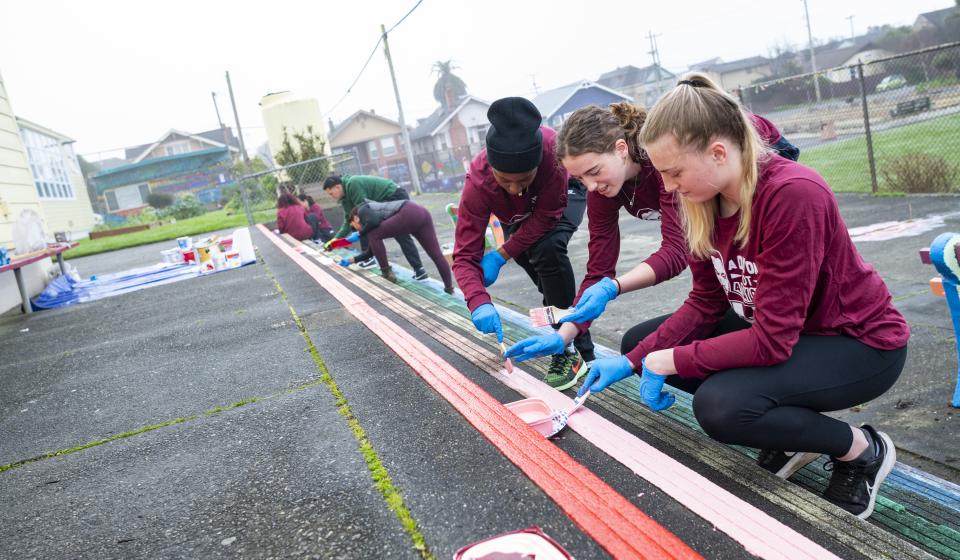 Women's basketball team volunteers paint the rainbow stairs at Jefferson. 