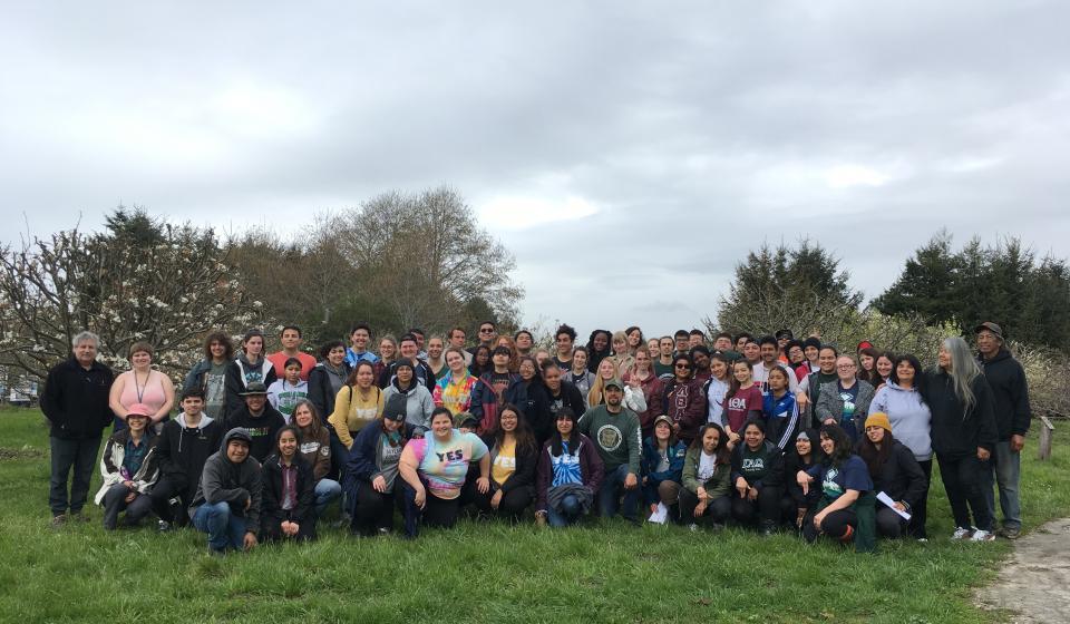 Large group of volunteers gather in the orchard at Potawot Community Food Gardens (Spring 2019)